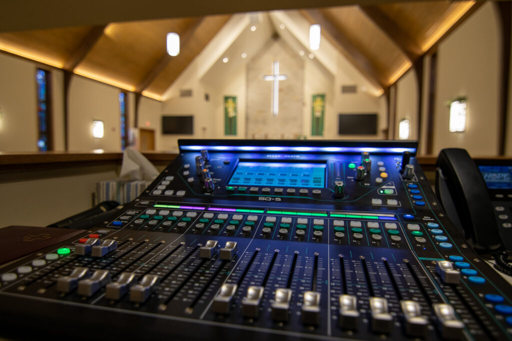 A close up of the sound mixing board, an SQ5 from Allen & Heath, a part of the worship system with the main platform blurred in the background.